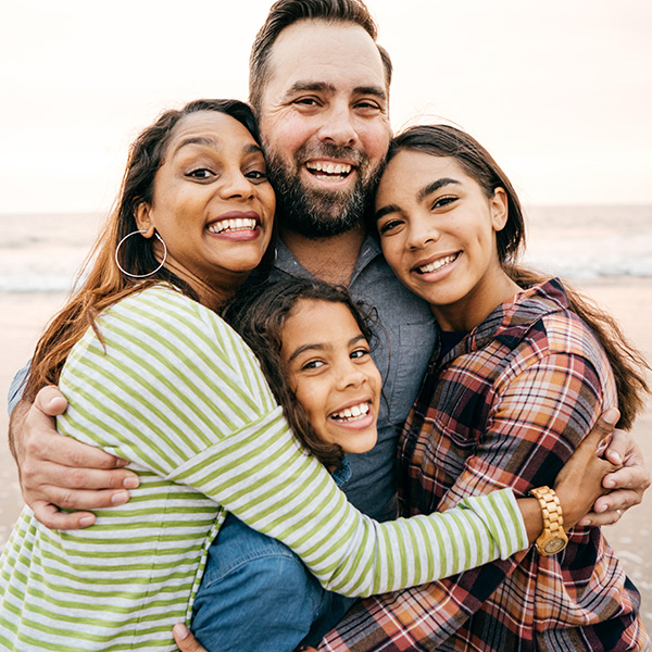 Happy family smiling showing their white teeth at the beach