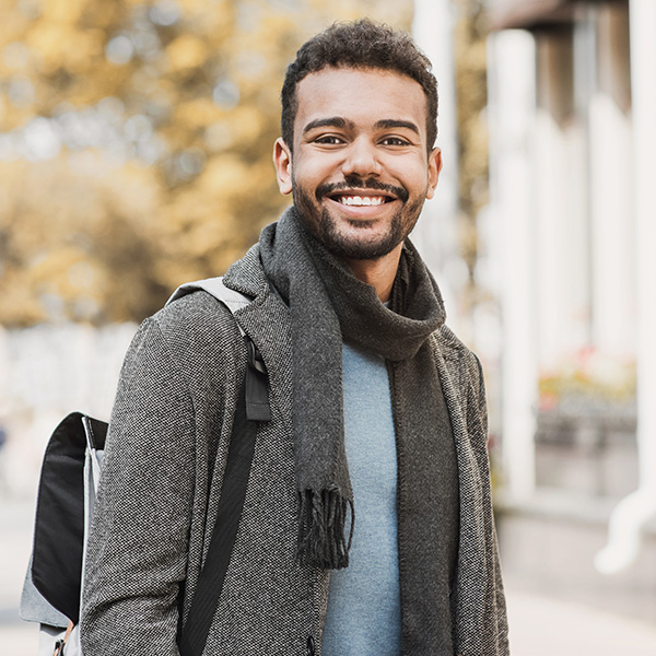 Man smiling showing his white teeth wearing a coat