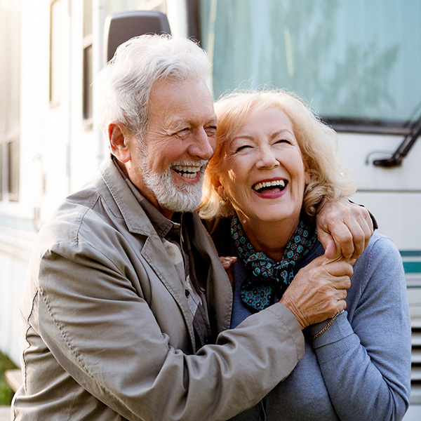 Happy couple smiling showing their white teeth outside RV