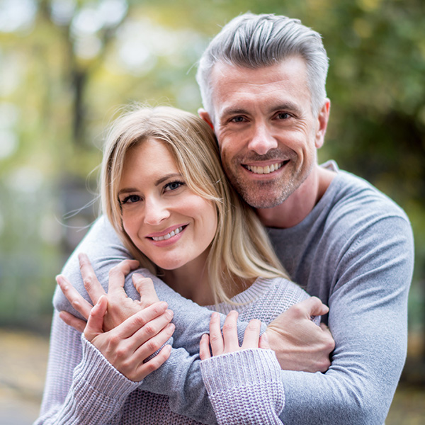 Happy couple smiling showing their white teeth in the park