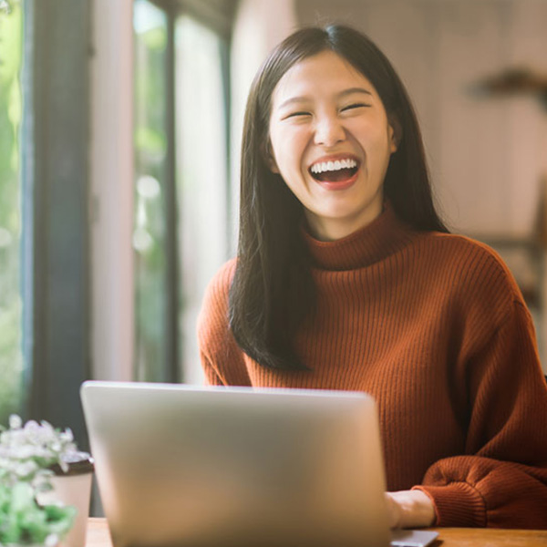 Woman smiling showing her white teeth working on computer