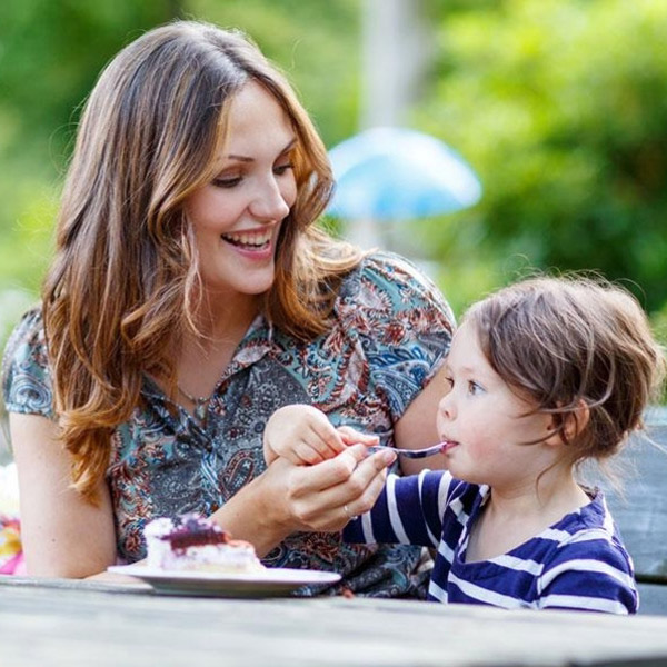 mom helping her child eat cake