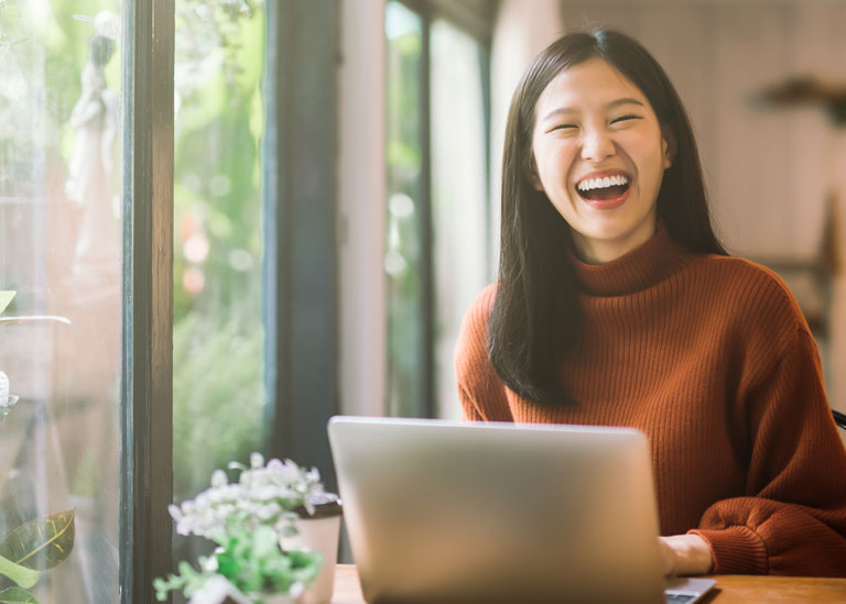 woman laughing while working on computer