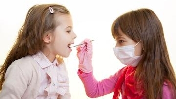 A small girl checking the teeth of another girl as COVID-19 safety precautions in Northern Phoenix