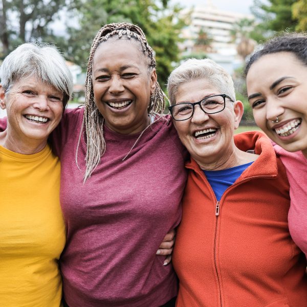 group of three elderly women and young girl smiling in park