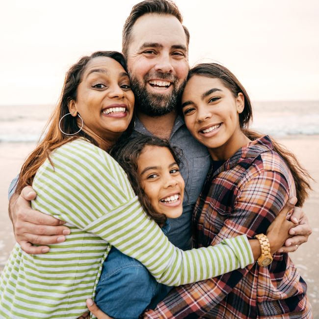 happy family of four smiling on the beach