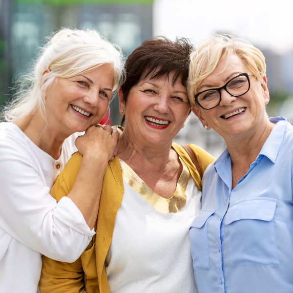 three elderly women smiling outdoors
