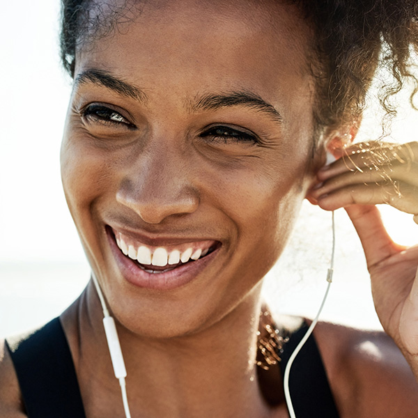 Woman smiling showing her white teeth and listening to music