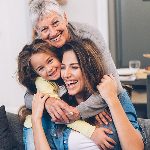 Happy grandma, daughter, and granddaughter smiling showing their white teeth